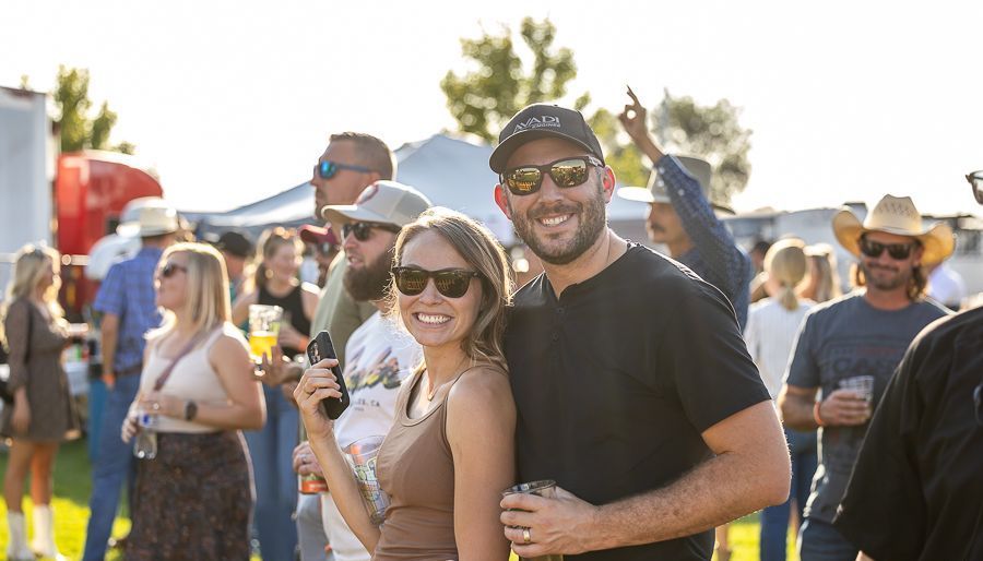 A man and a woman are posing for a picture in front of a crowd at a festival.