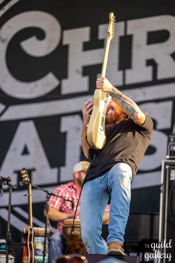 A man is playing a guitar in front of a sign that says chr