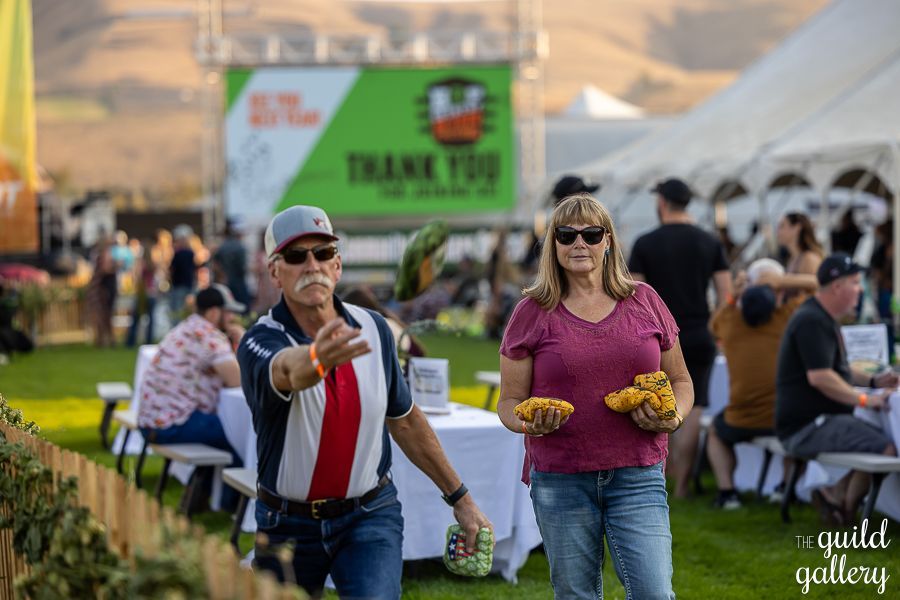 A man and a woman are walking in front of a thank you sign at a festival.