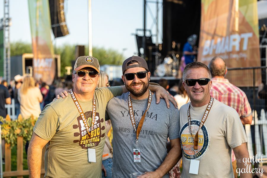 Three men are posing for a picture at a music festival.