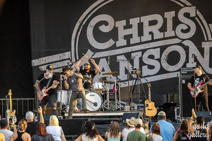 A group of people are standing on a stage in front of a large sign that says chris anson.
