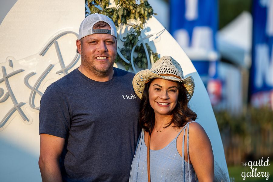 A man and a woman are posing for a picture . the woman is wearing a cowboy hat.