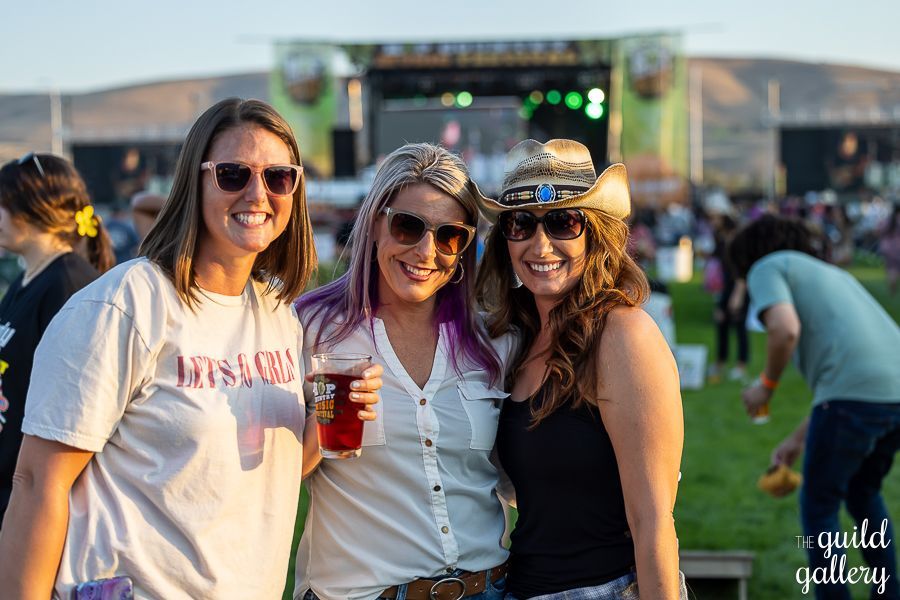 Three women are posing for a picture at a music festival.