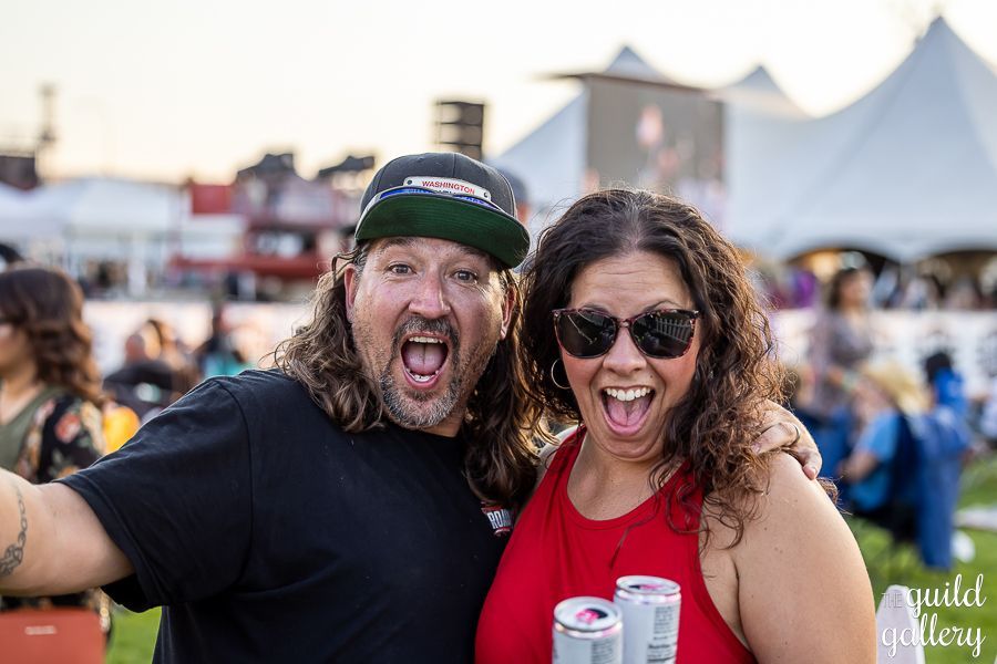 A man and a woman are posing for a picture at a festival.