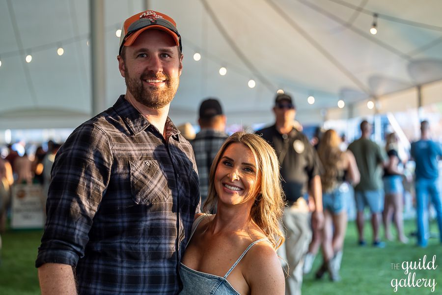 A man and a woman are posing for a picture in front of a crowd.