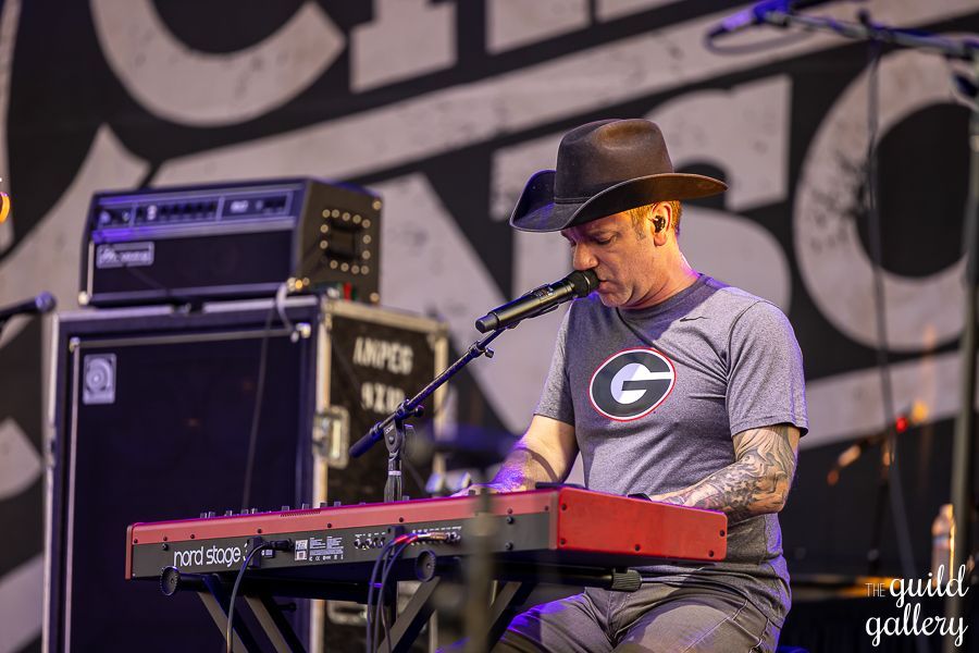 A man in a cowboy hat is playing a keyboard on stage.
