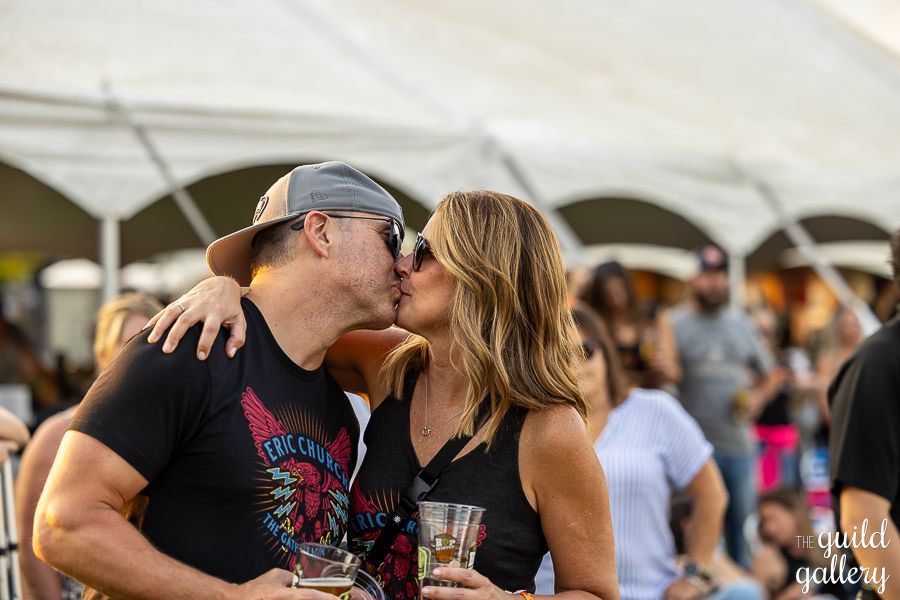 A man and a woman are kissing in front of a crowd at a concert.