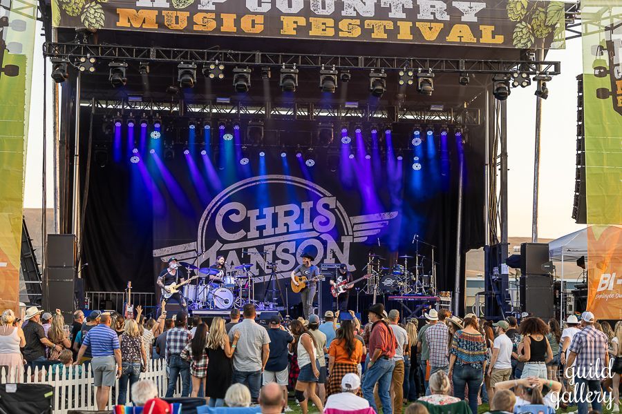 A group of people are standing in front of a stage at a country music festival.