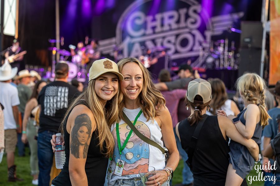 Two women are posing for a picture at a concert.