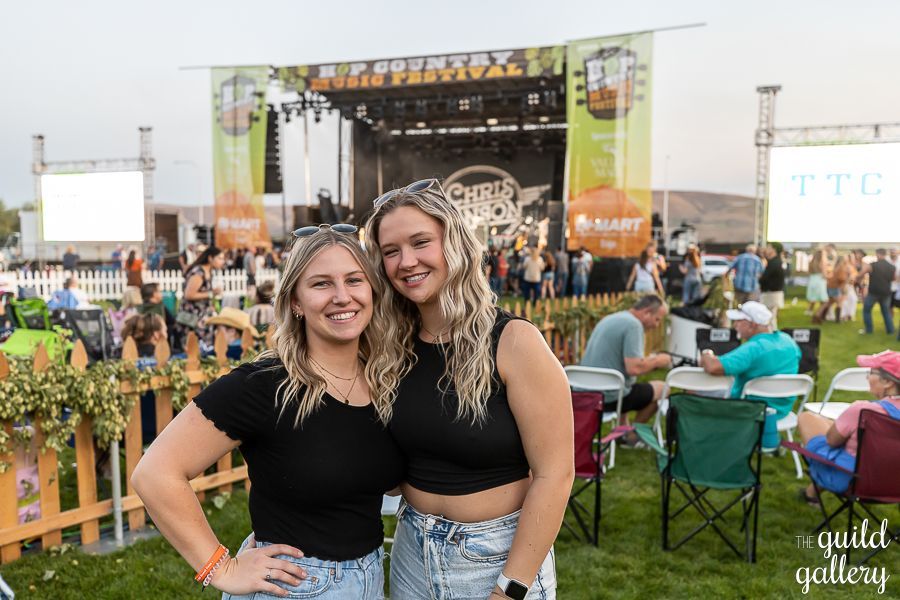 Two women are standing next to each other in front of a crowd at a concert.