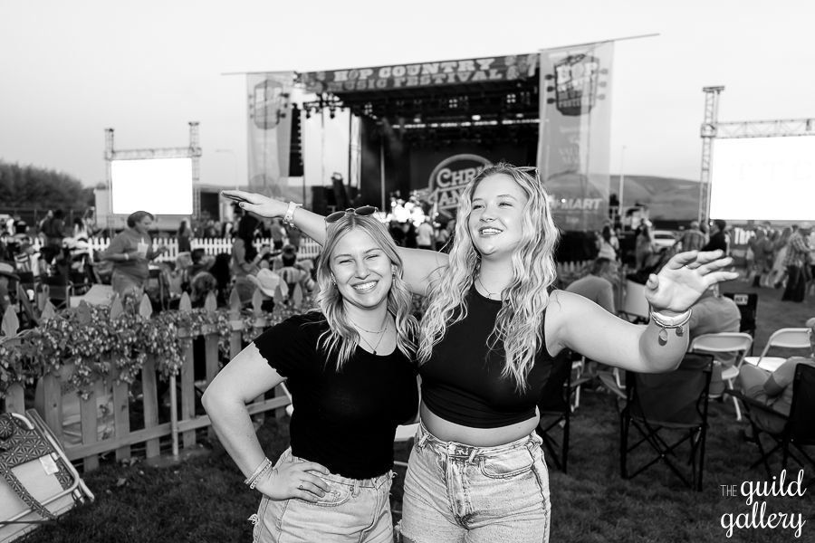 Two women are posing for a picture in front of a crowd at a concert.