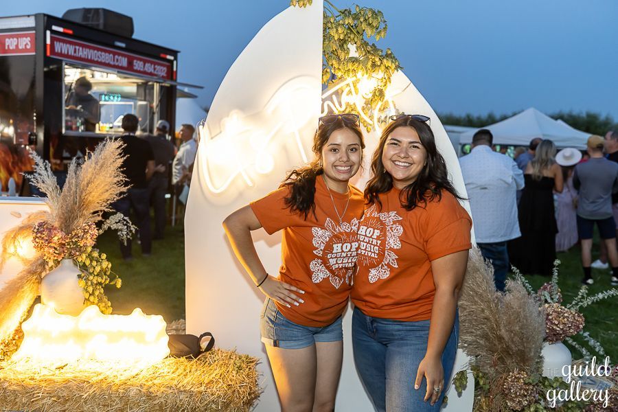 Two women are posing for a picture in front of a food truck.