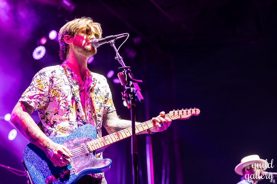 A man is playing a guitar and singing into a microphone on a stage.
