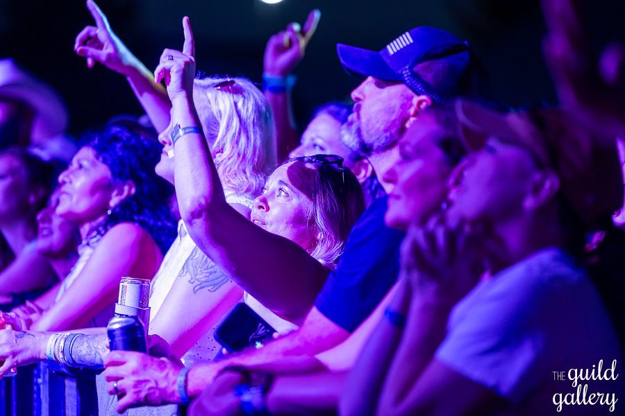 A group of people are sitting in a dark room watching a concert.