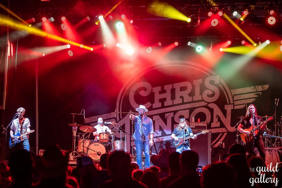 A group of people playing instruments on a stage in front of a sign that says chris johnson