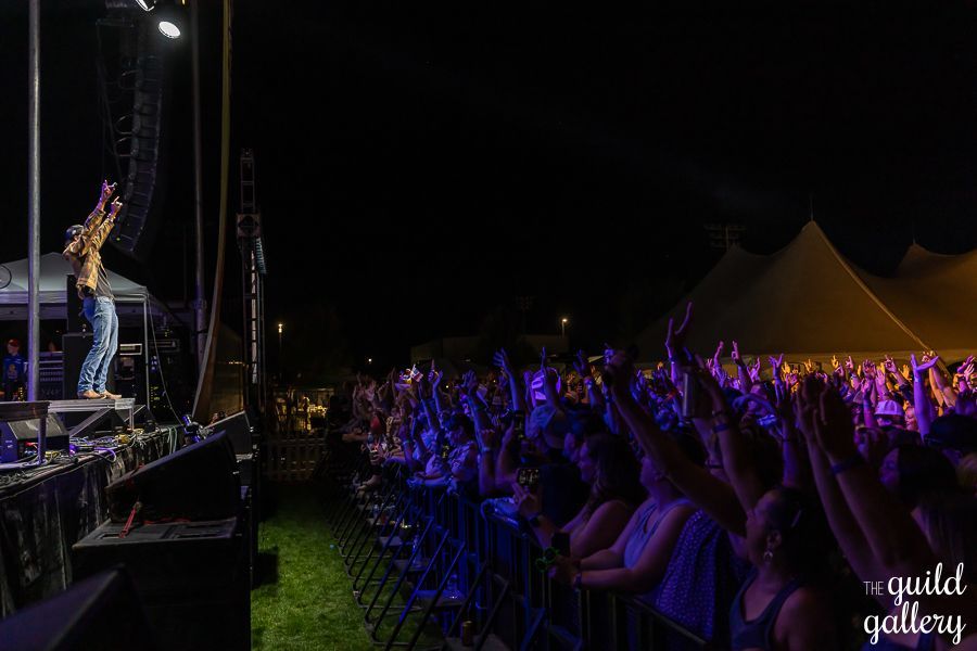A man is standing on a stage in front of a crowd at a concert.