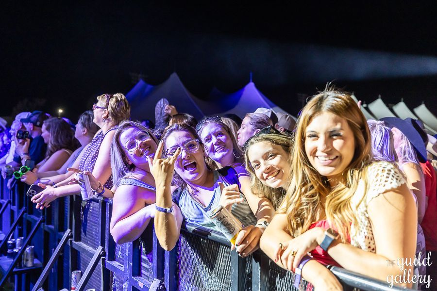 A group of women are posing for a picture at a concert.