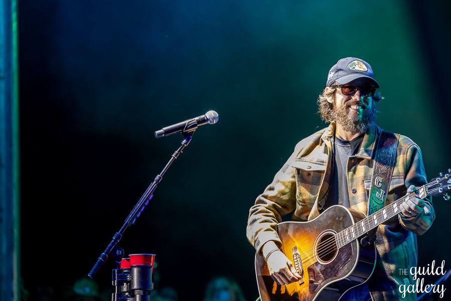 A man is playing a guitar and singing into a microphone on a stage.