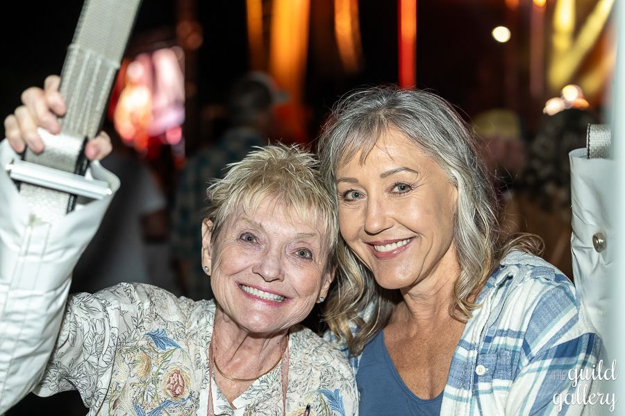 Two older women are posing for a picture together at a party.