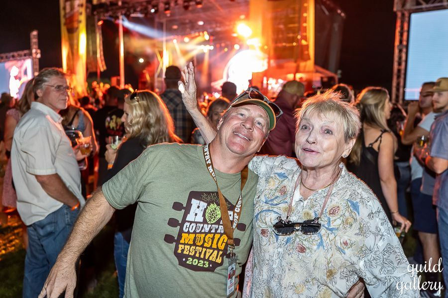 A man and a woman are posing for a picture at a music festival.