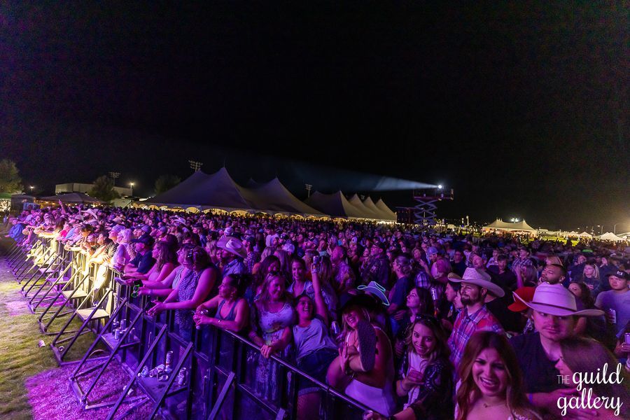 A large crowd of people are sitting in front of a stage at a concert.