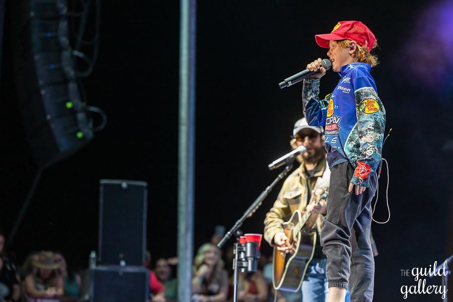 A man is playing a guitar and singing into a microphone on a stage.