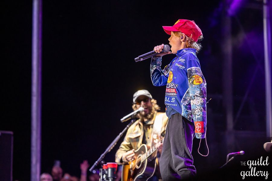 A man is playing a guitar and singing into a microphone on a stage.
