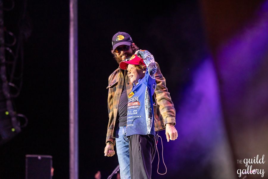 A man is holding a child on his shoulders on a stage.