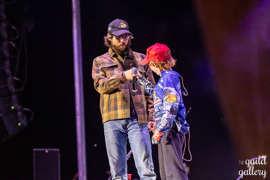 A man and a child are standing on a stage in front of a microphone.