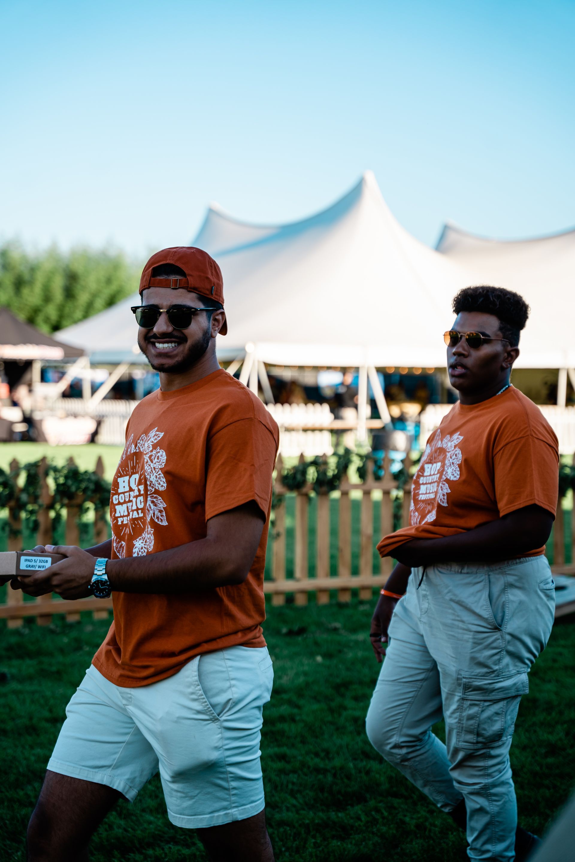 Two men are standing next to each other in a field in front of a tent.