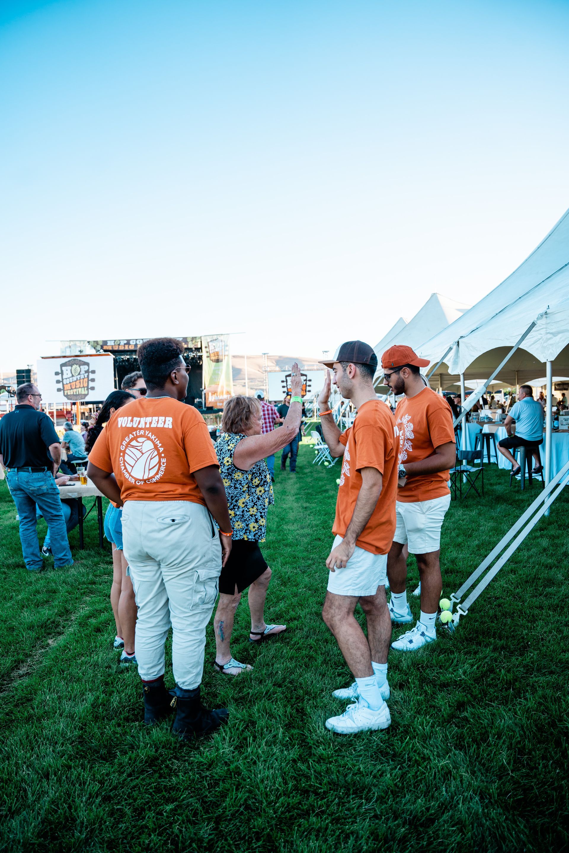 A group of people are standing in a grassy field talking to each other.