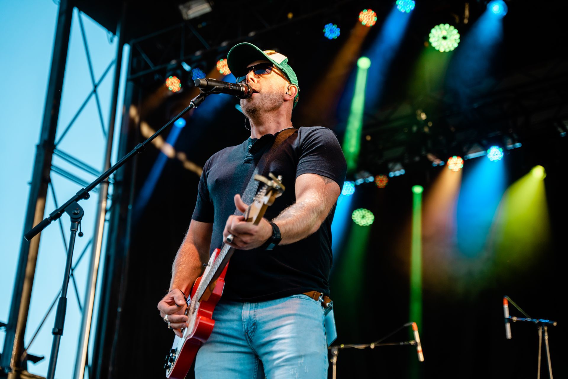 A man is playing a guitar and singing into a microphone on a stage.