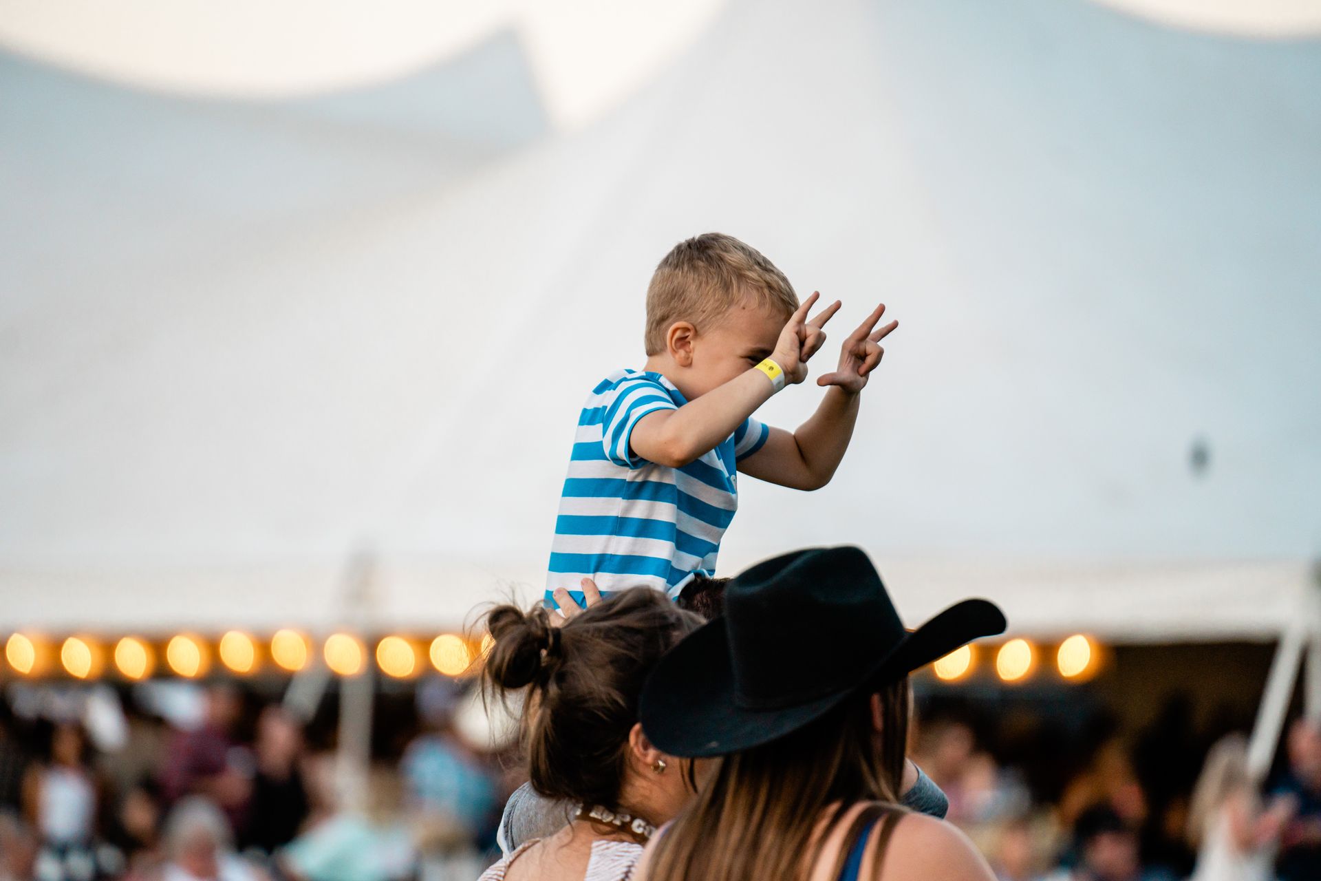 A woman is holding a little boy on her shoulders.