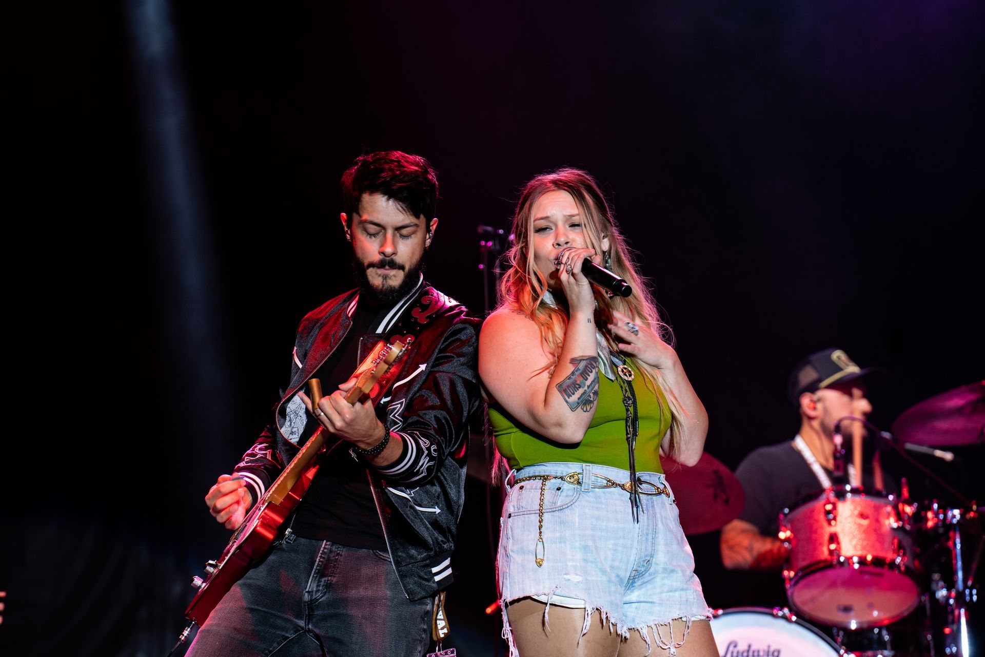 A man is playing a guitar and a woman is singing on a stage.