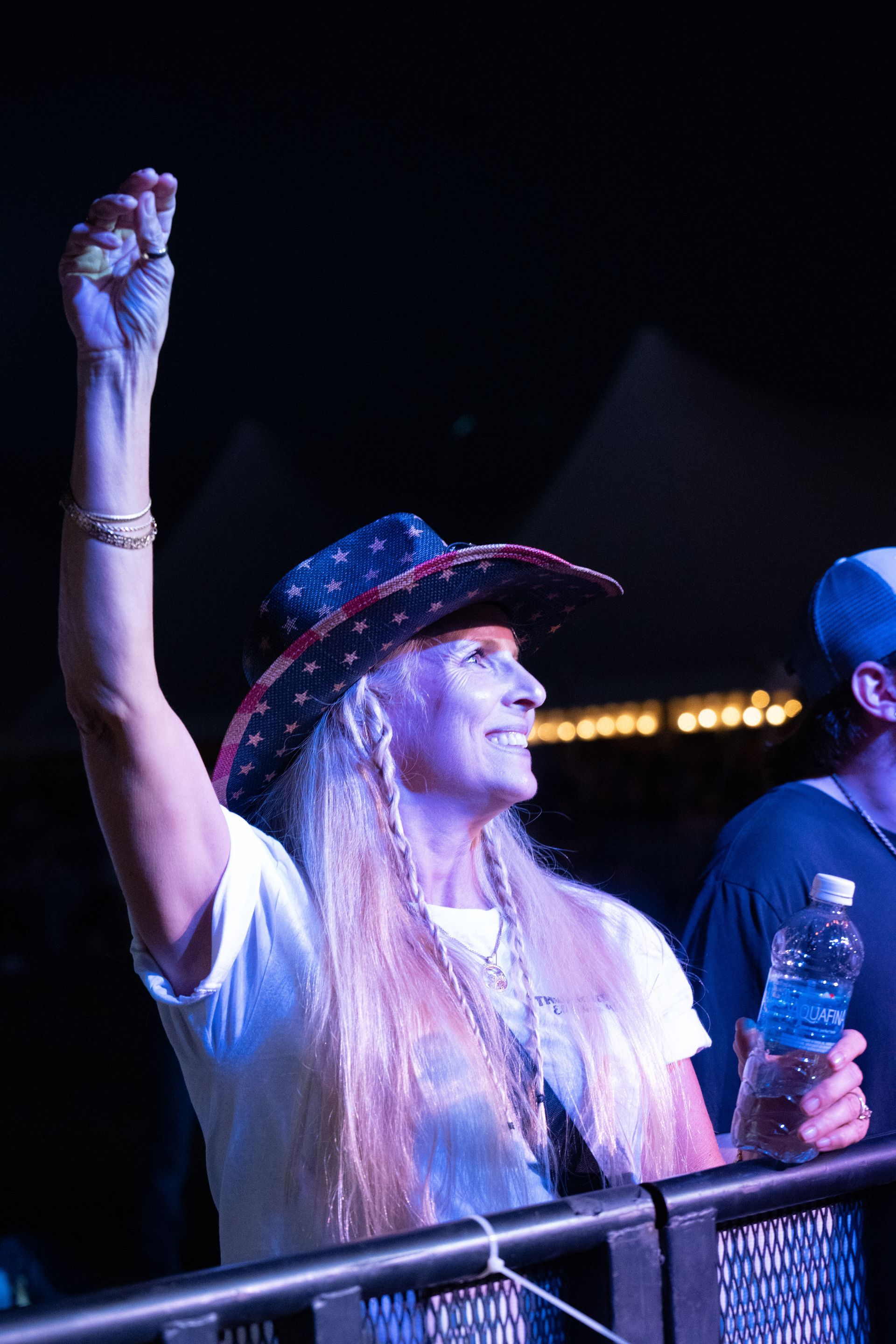 A woman in a cowboy hat is holding a bottle of water.