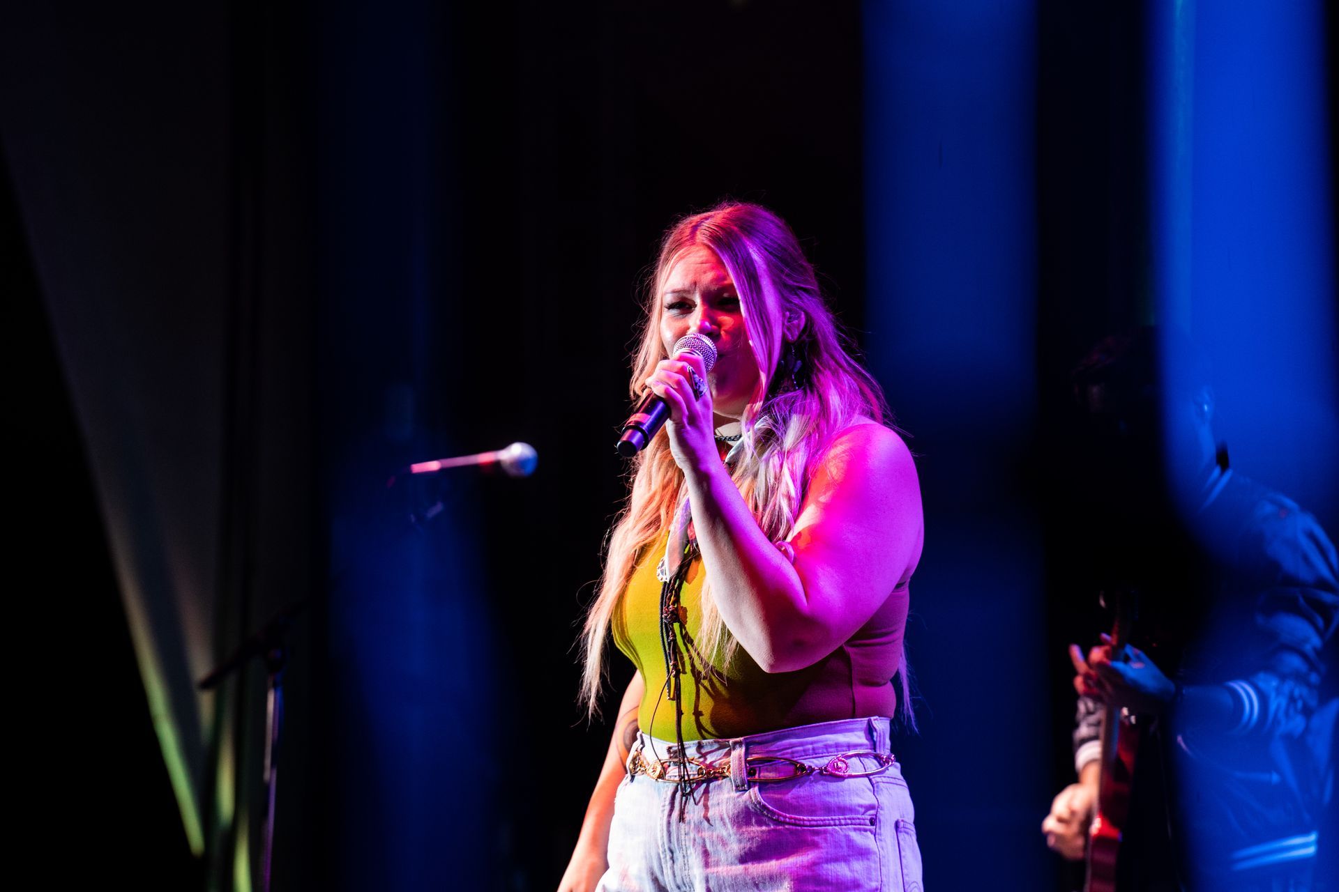 A woman is singing into a microphone on a stage.