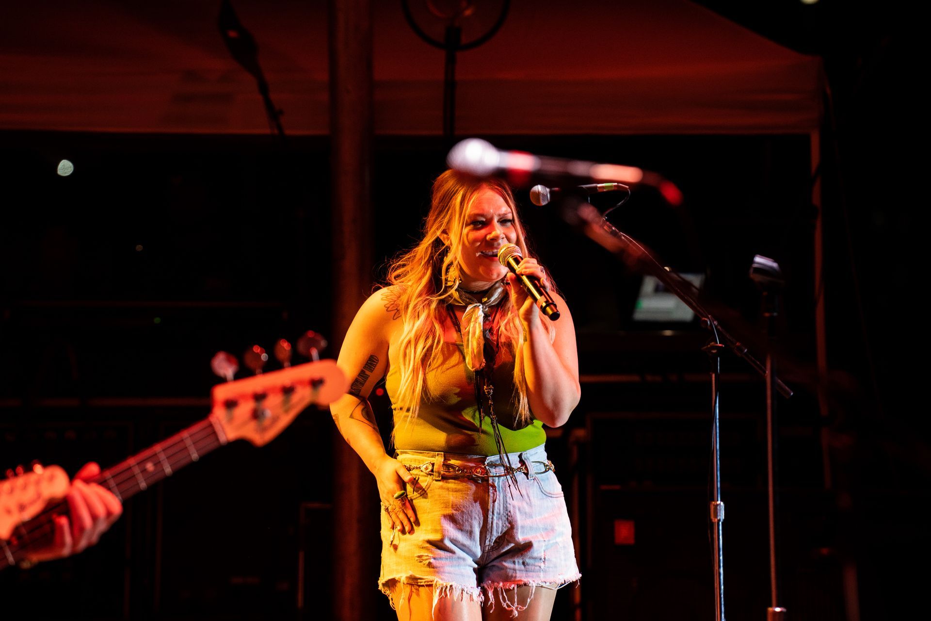 A woman is singing into a microphone while playing a guitar on stage.