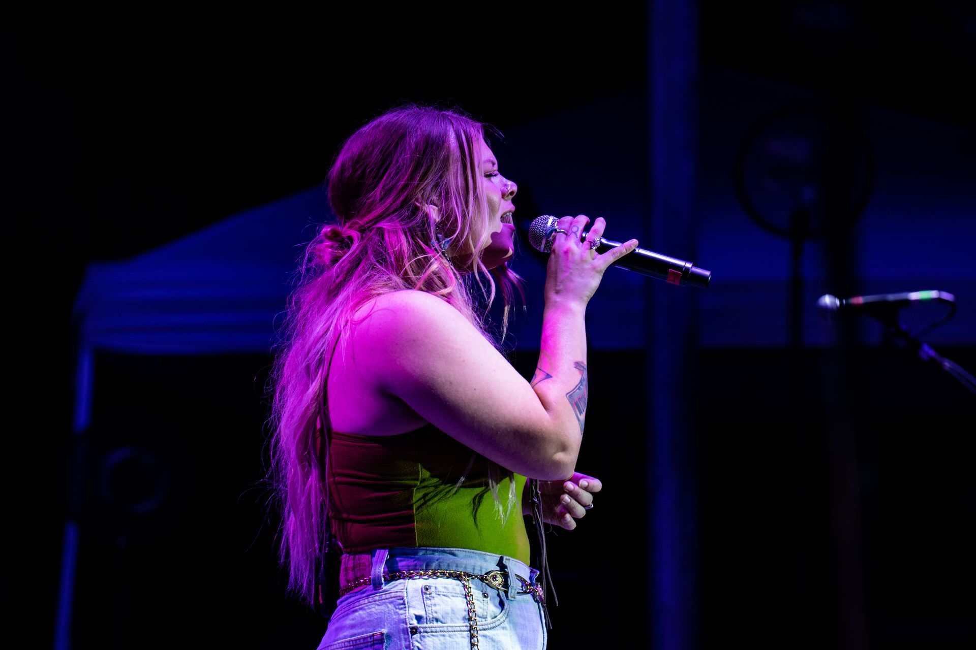 A woman is singing into a microphone on a stage.