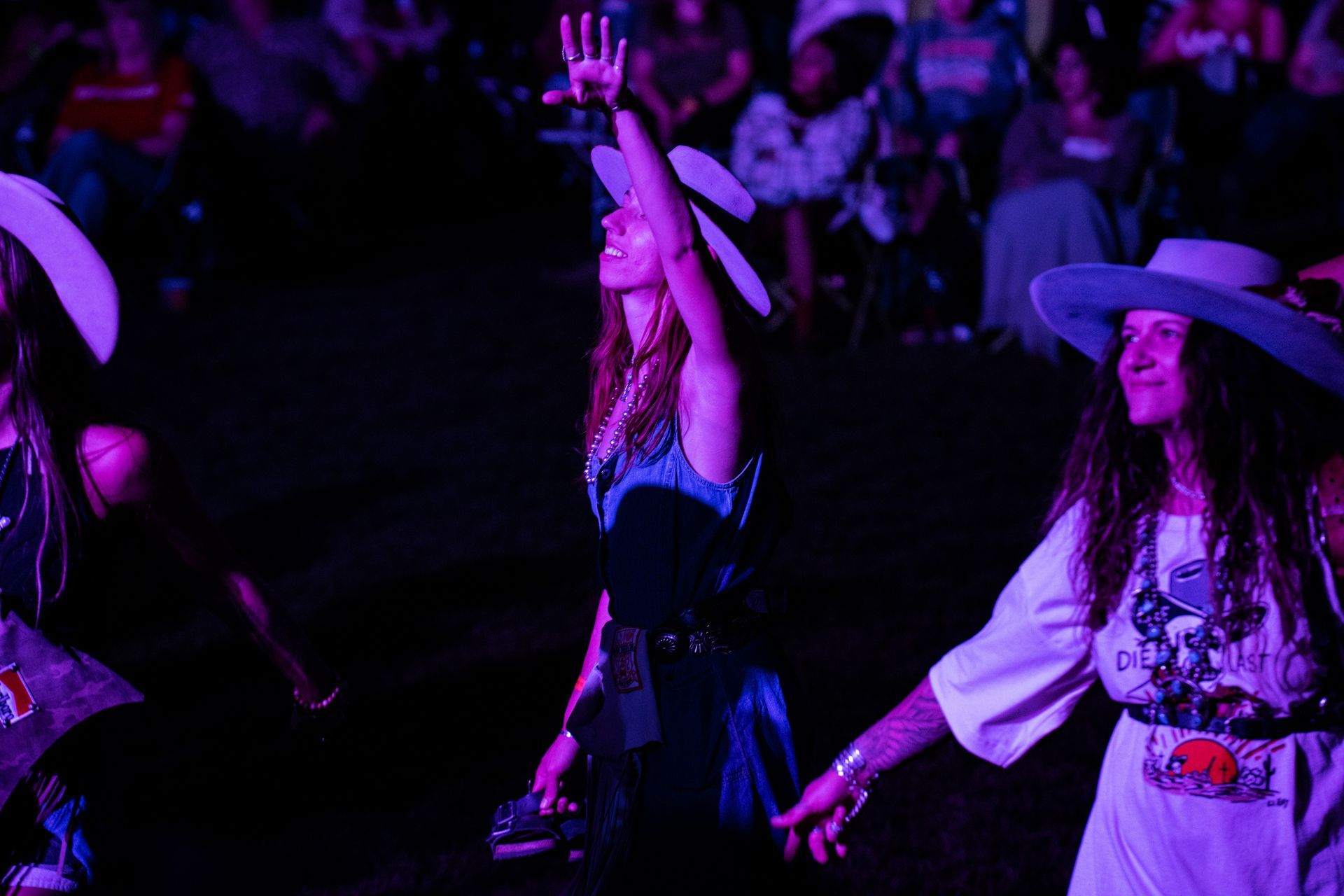 A group of women are dancing in a dark room with purple lights.