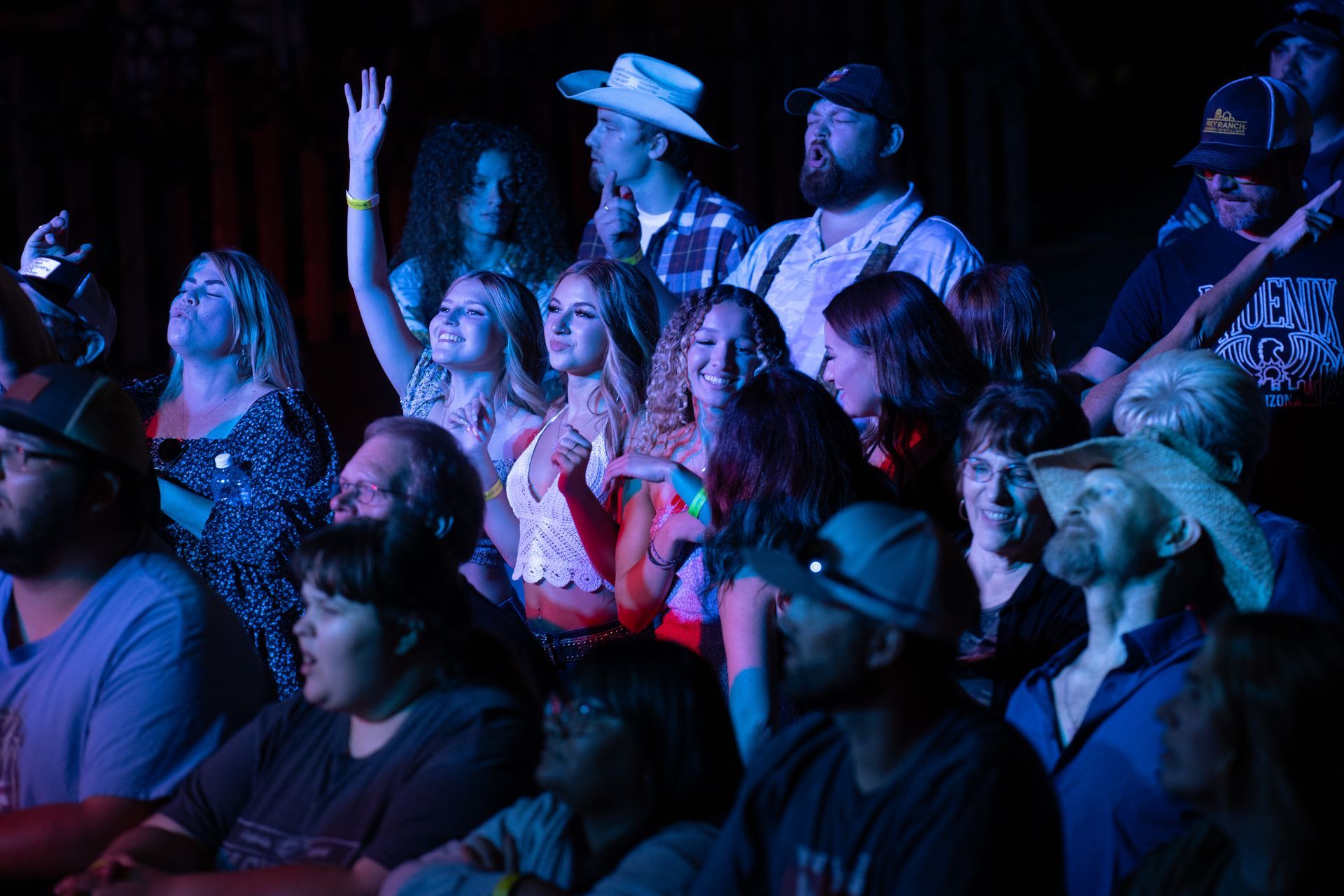 A large group of people are sitting in a dark room watching a concert.