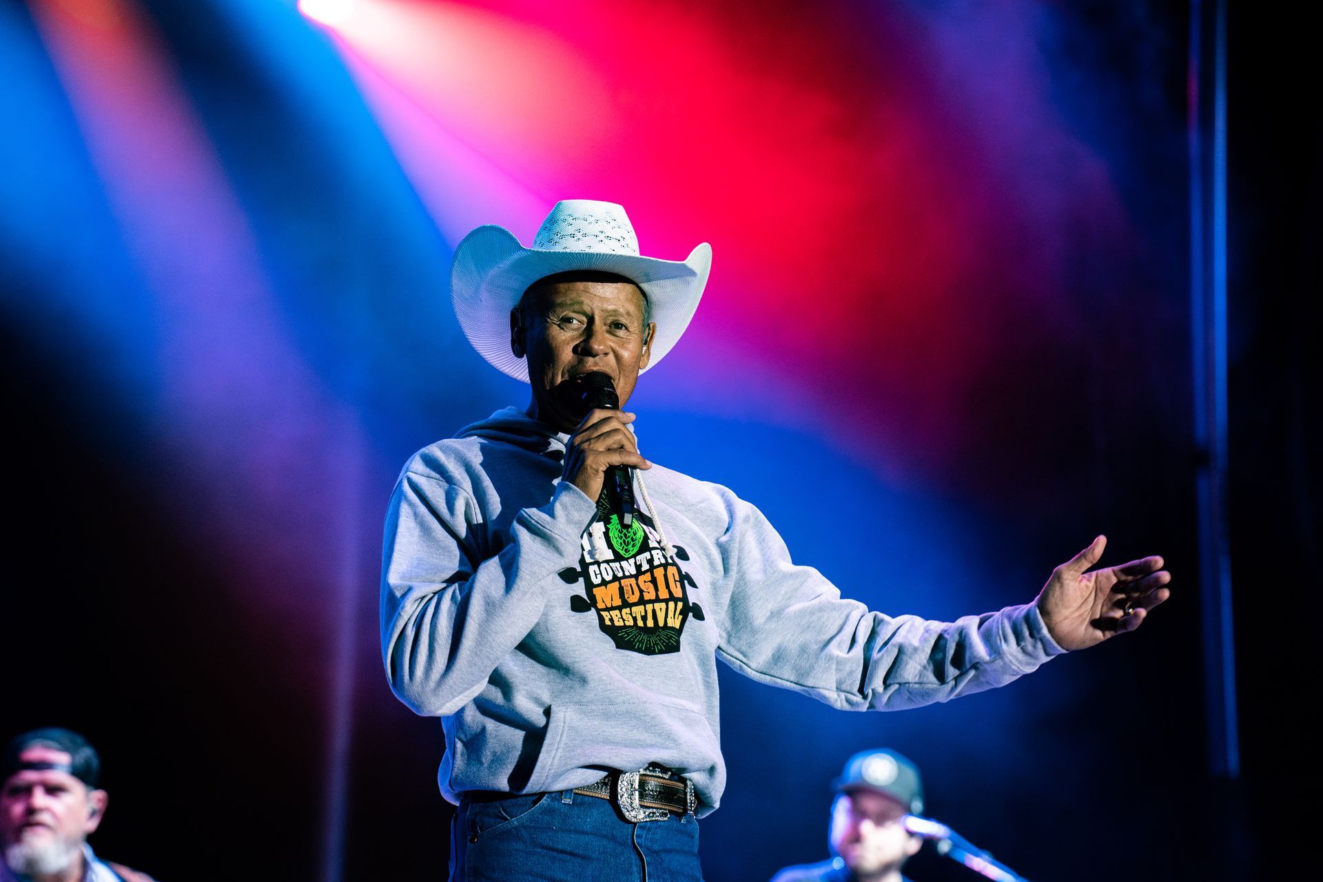 A man in a cowboy hat is singing into a microphone on a stage.