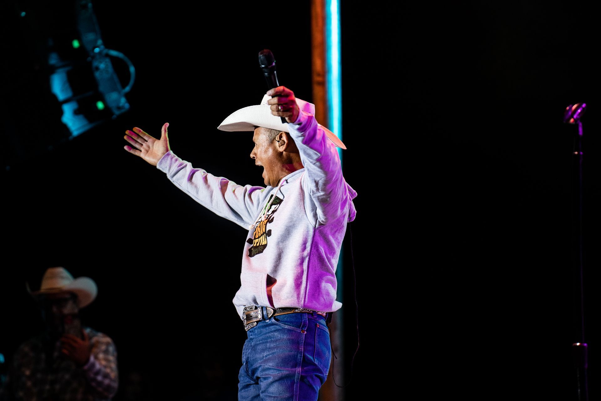 A man in a cowboy hat is singing into a microphone on a stage.