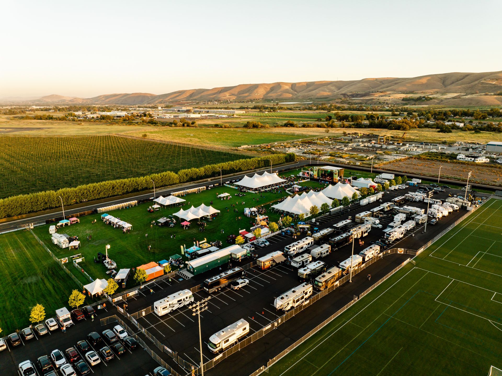 An aerial view of a parking lot filled with cars and tents.
