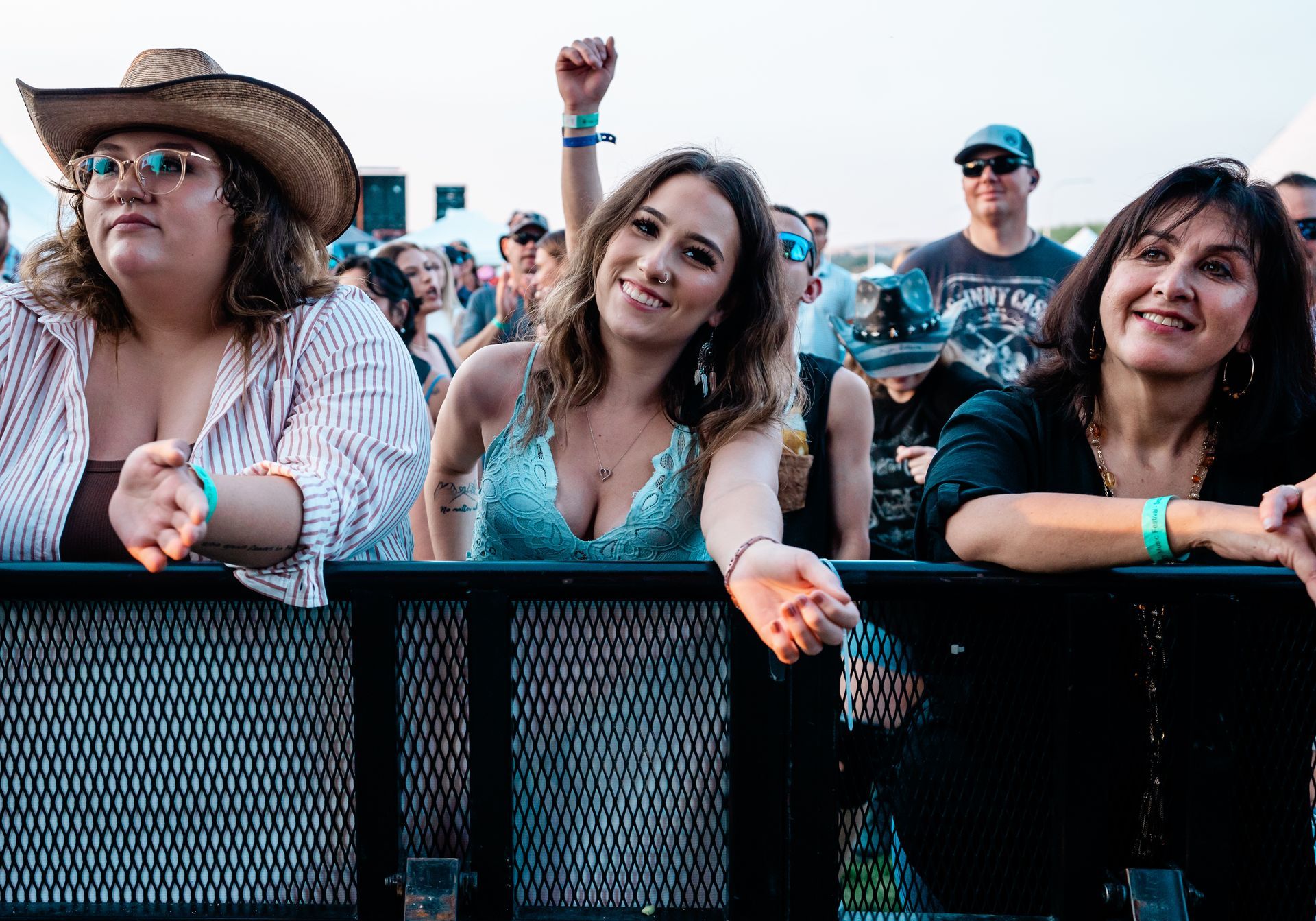 A group of women are standing behind a fence at a concert.