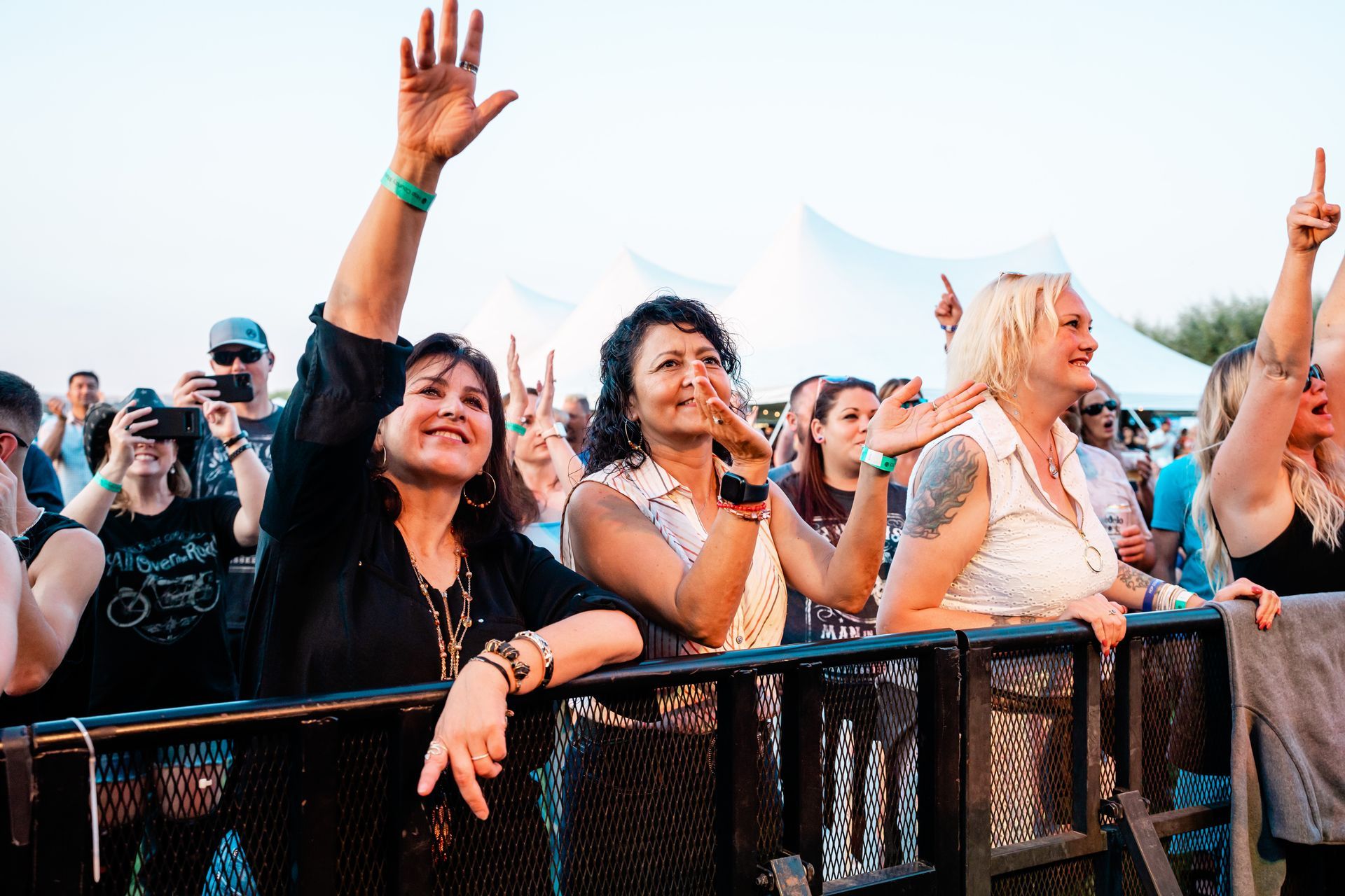 A crowd of people are standing behind a fence at a concert.