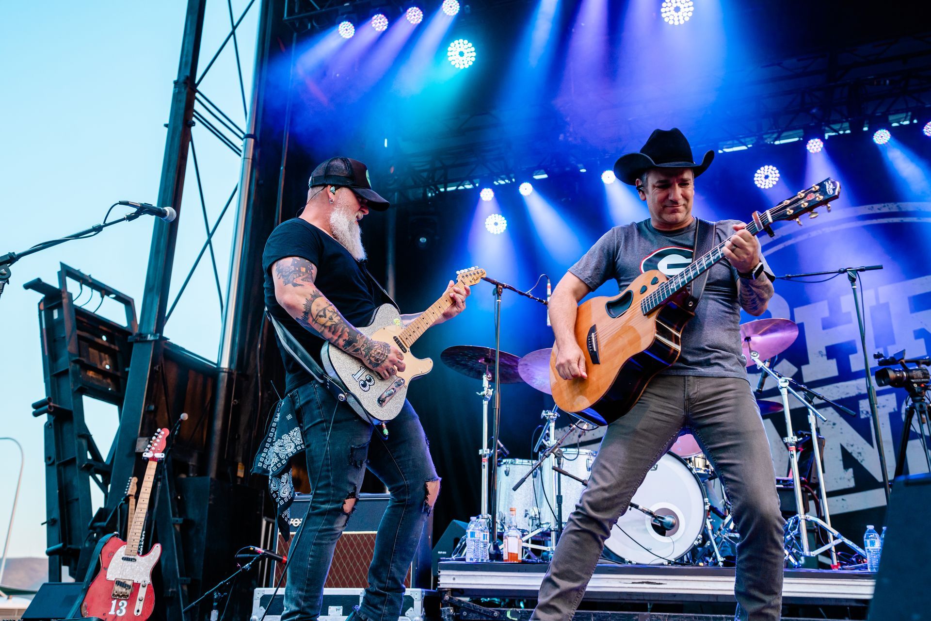 Two men are playing guitars on a stage.