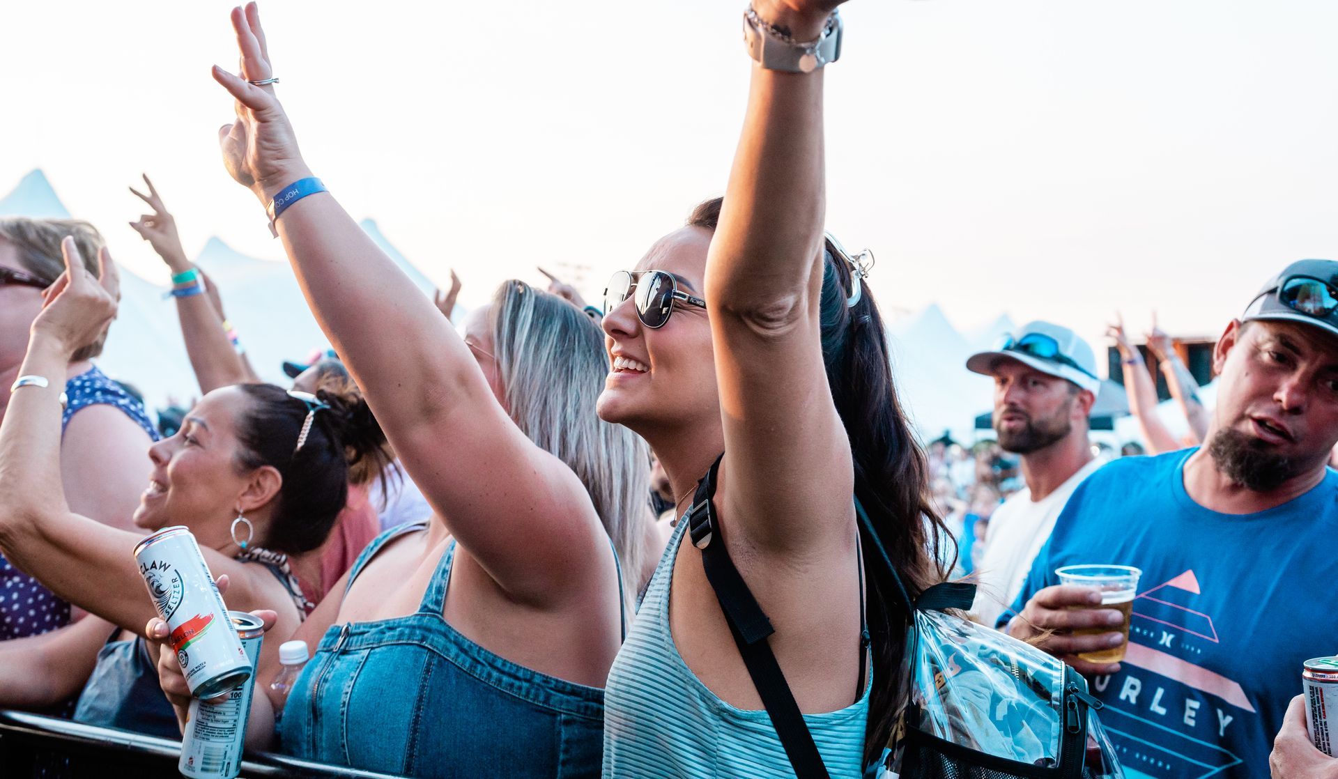A woman is raising her arms in the air at a concert.