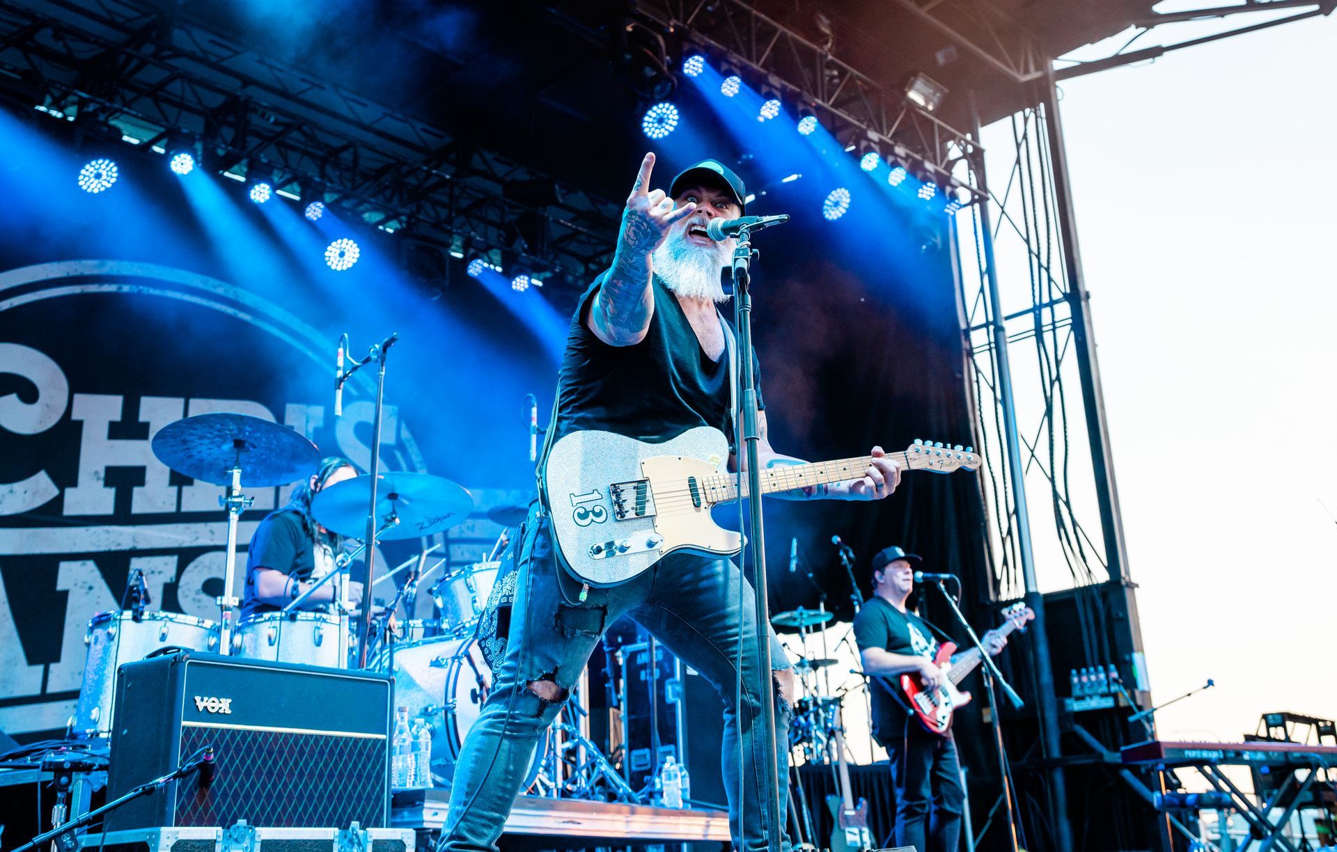 A man is singing into a microphone while playing a guitar on a stage.