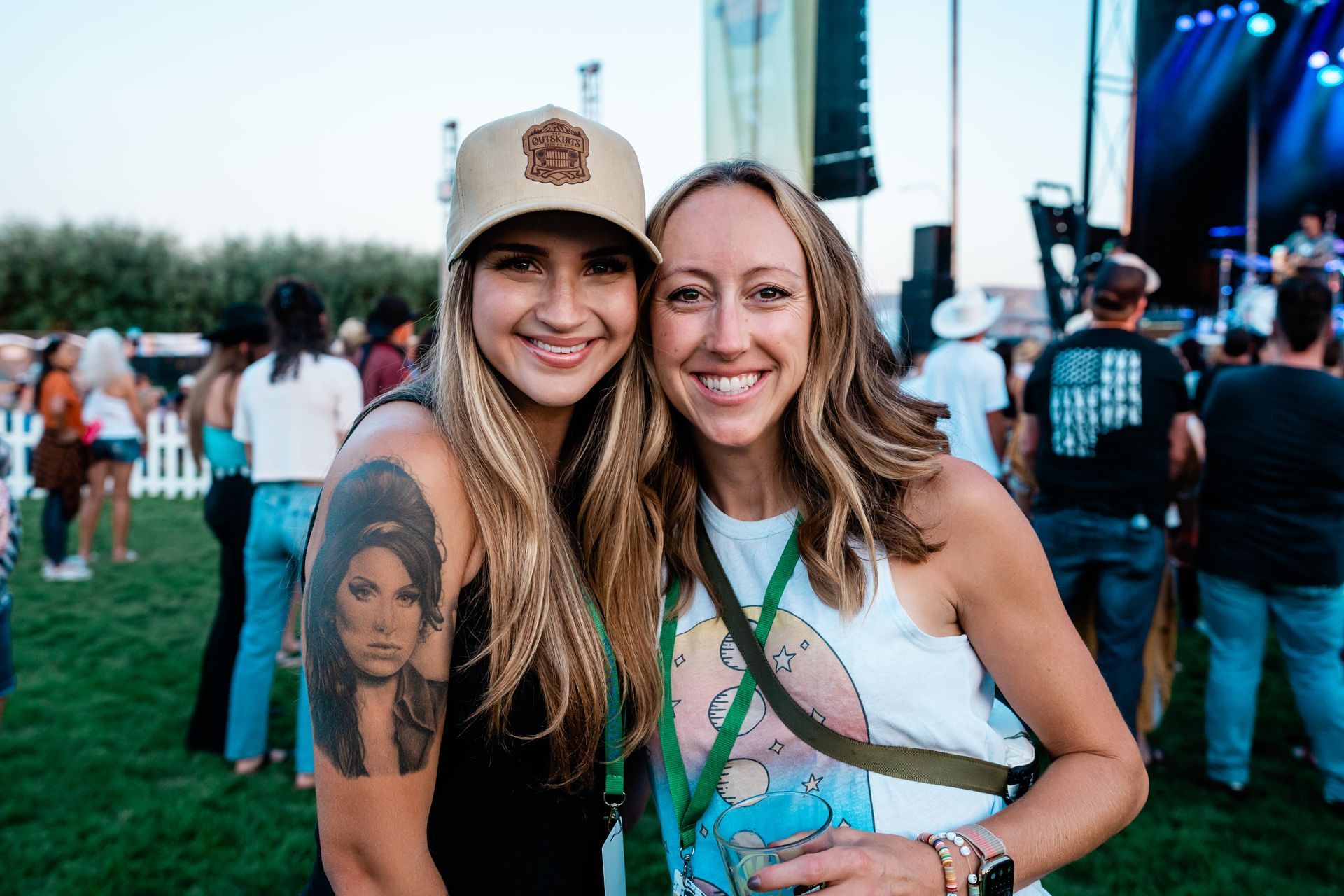Two women are posing for a picture together at a concert.