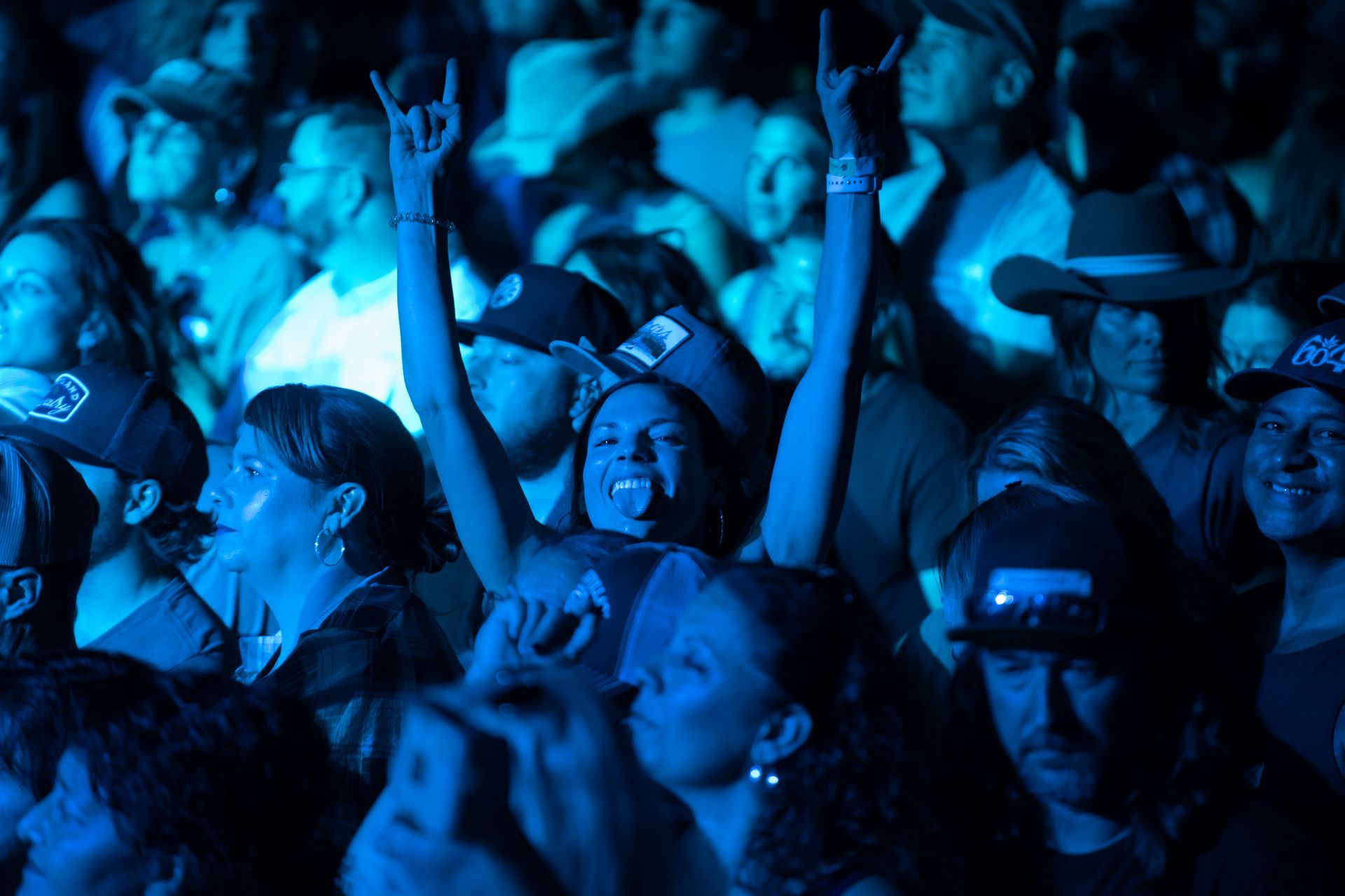 A crowd of people are watching a concert with their arms in the air.